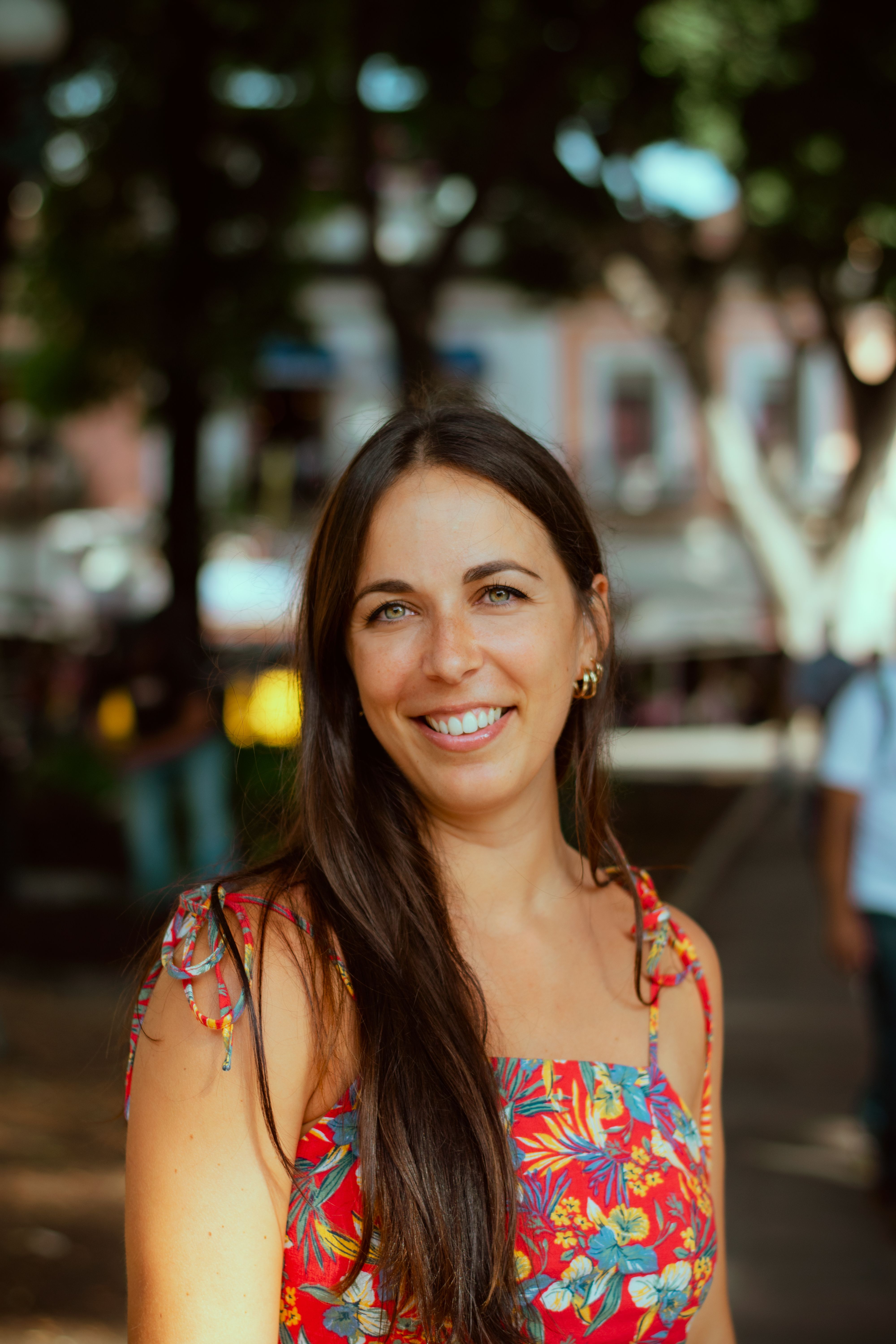 A person smiling outdoors wearing a flower shirt.
