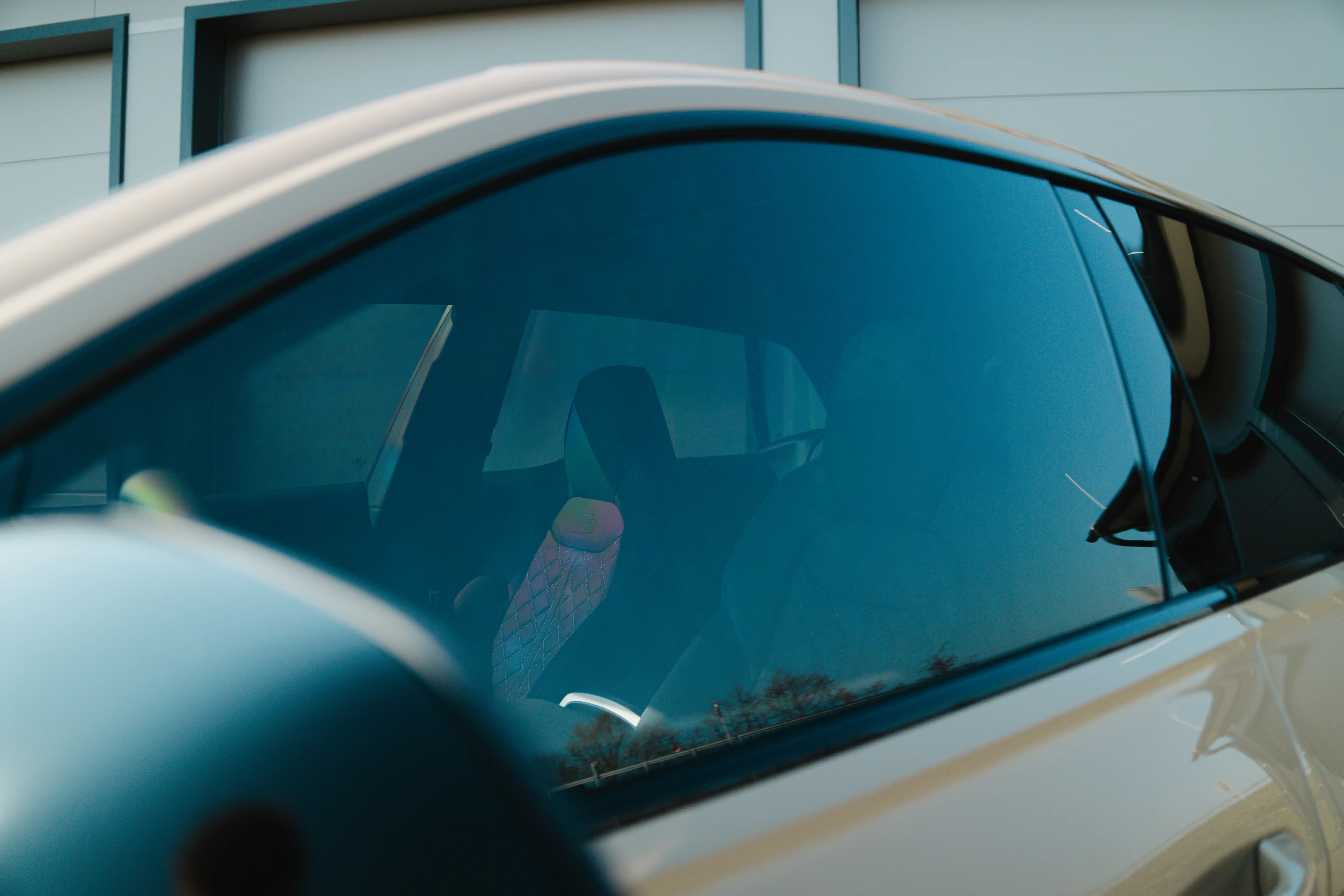 Detailaufnahme mit Blick durch die dezent getönten vorderen Seitenscheiben (55 %) in den Innenraum eines Audi Q8.