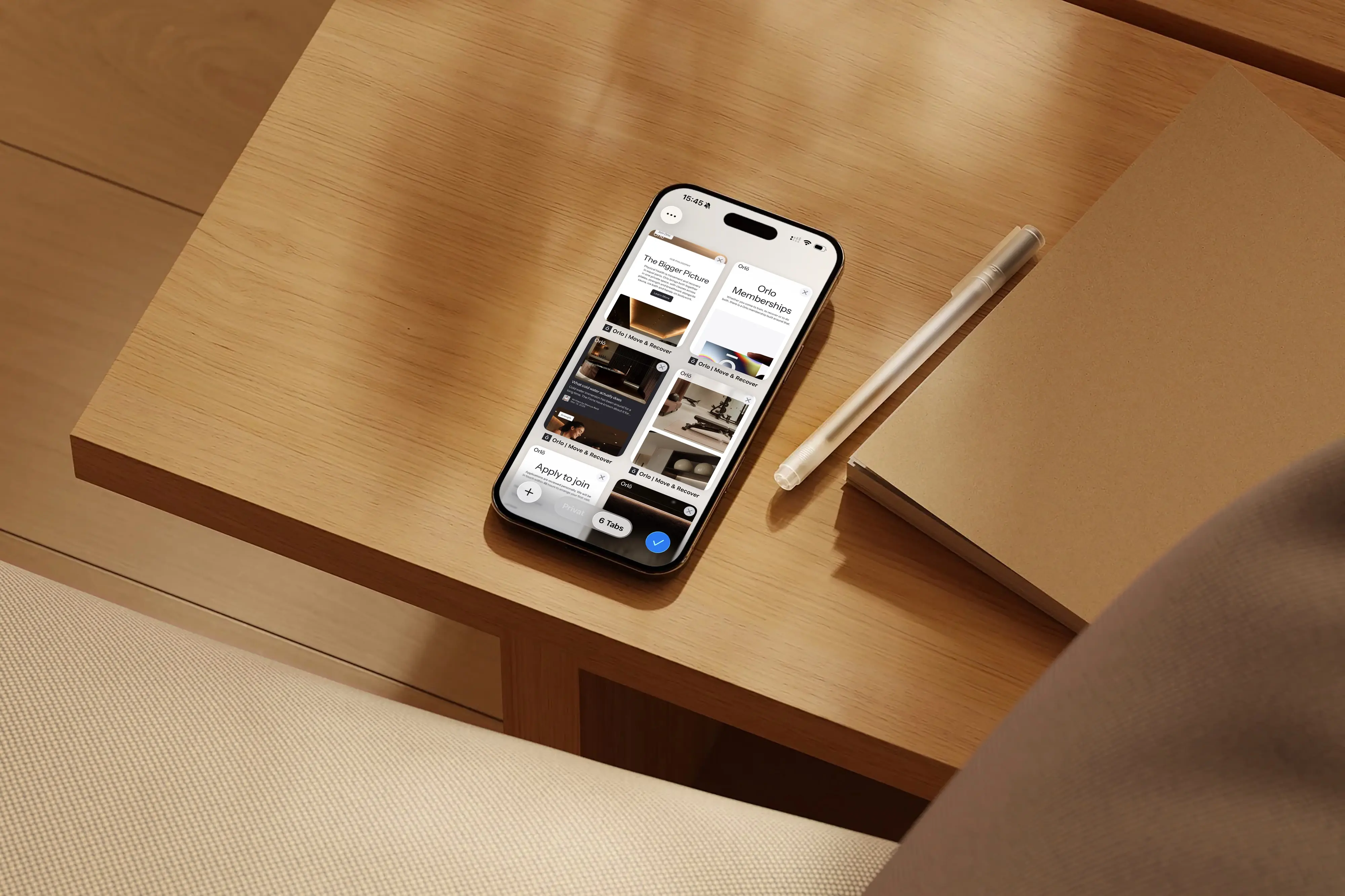 Phone showing six open browser tabs of the Orlō website, lying on a wooden table