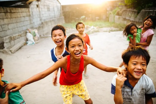 a group of smiling Southeast Asian children playing in a street