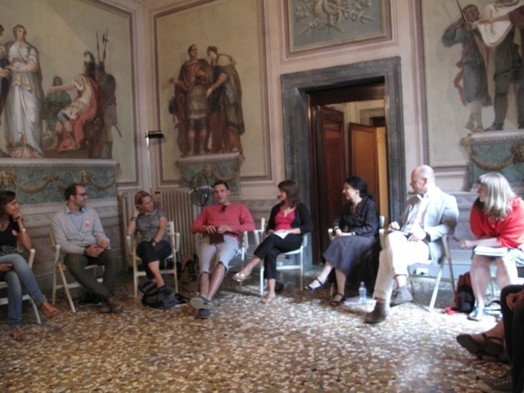 A photo of a group of people talking while sitting in a renaissance era room.