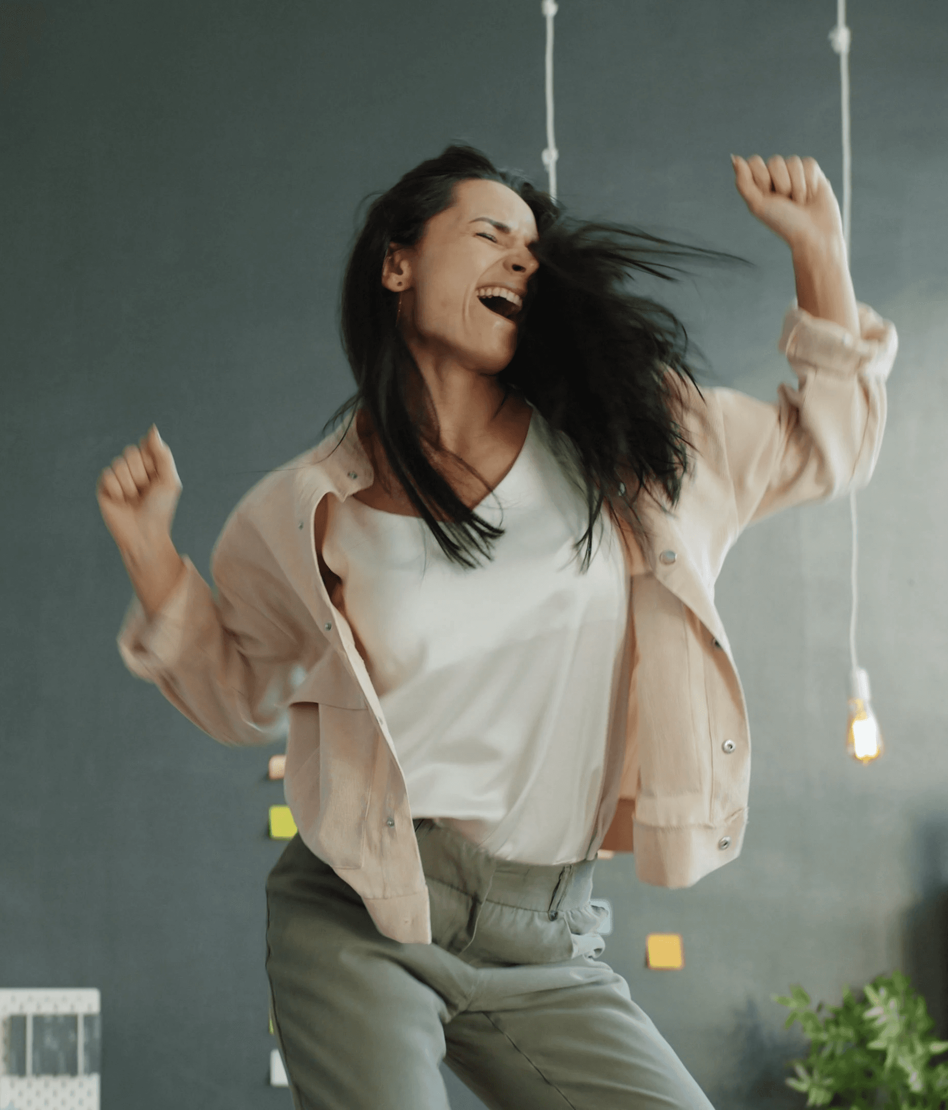 A woman joyfully dancing with arms raised.