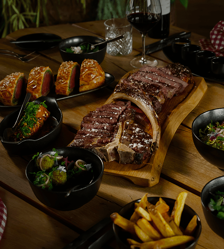 Šťavnatý grilovaný steak servírovaný s hranolkami, zeleninou a červeným vínem v moderní restauraci.