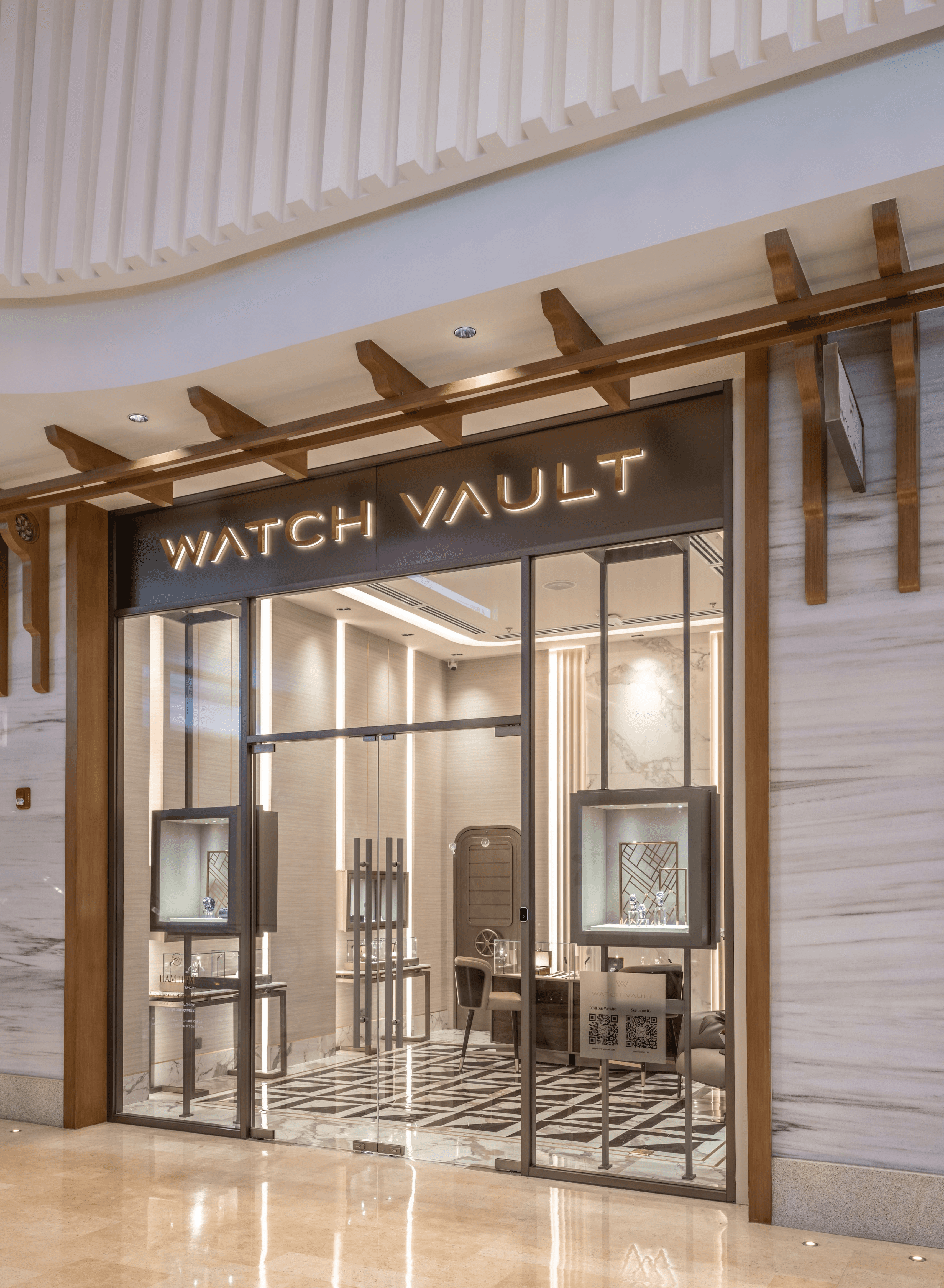 Modern storefront with glass doors and wooden accents, featuring two interactive displays inside.