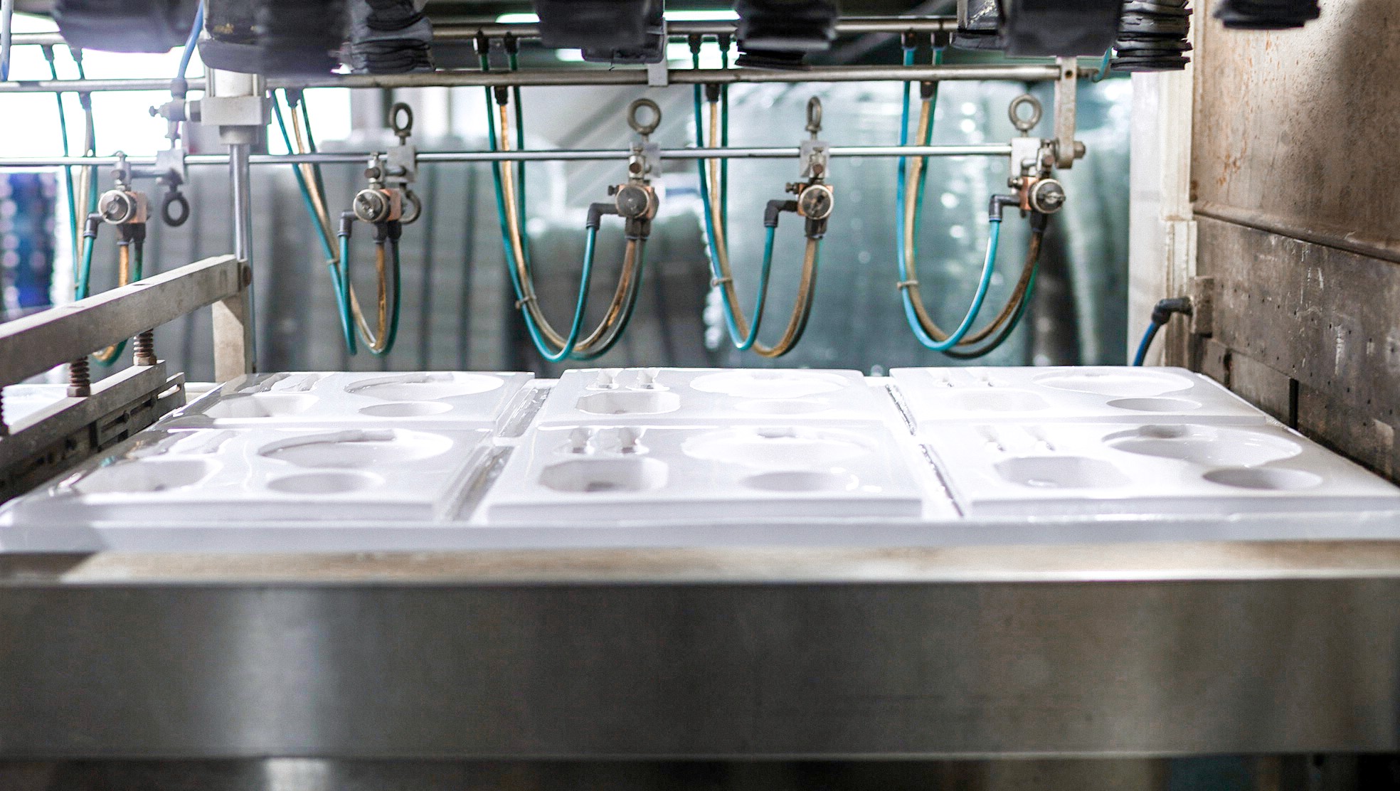 Tangan operator memeriksa hasil cetakan kemasan plastik menggunakan teknologi vacuum forming pada lembaran plastik transparan – proses manufaktur blister packaging presisi.