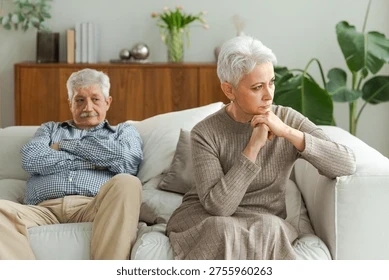 Disappointed older couple sitting on the couch.