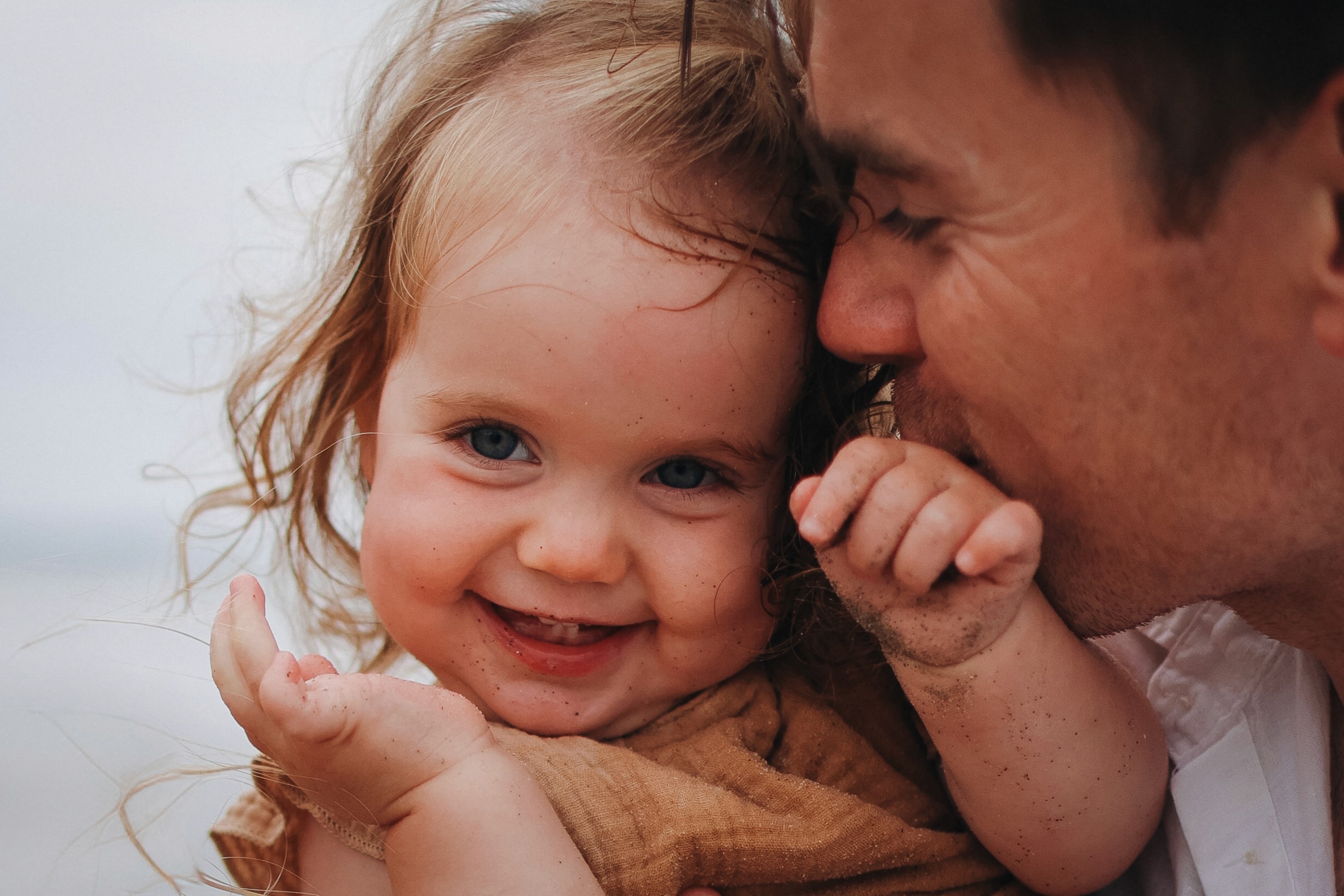 Dad lifting her toddler daughter during a joyful moment on the beach