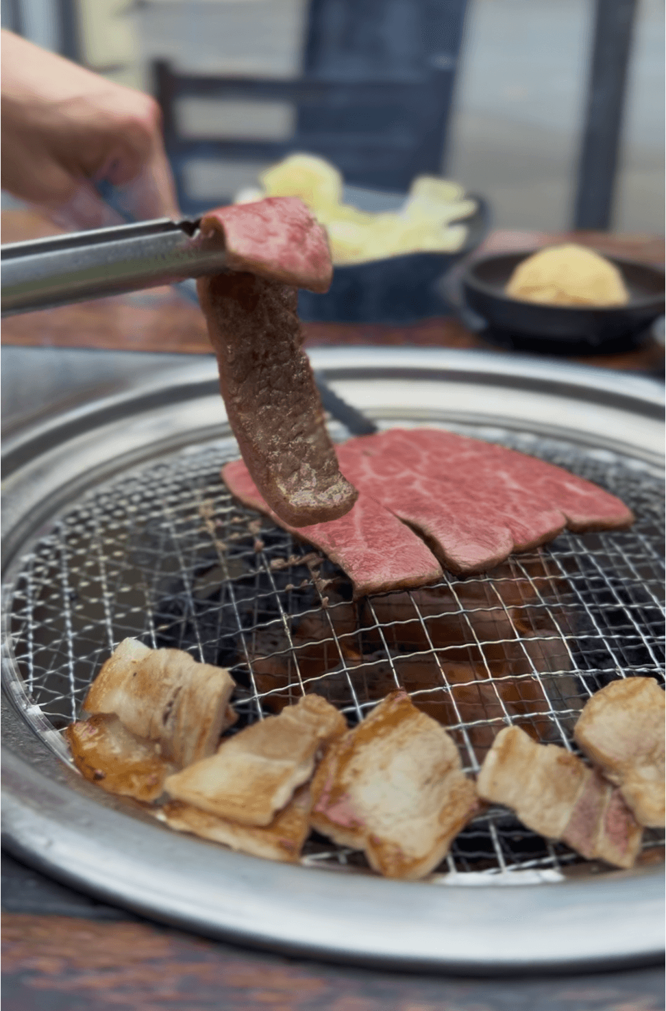 A large, perfectly seared fillet of salmon with crispy skin and a herb glaze, garnished with microgreens, fresh dill, and lemon wedges, presented on a dark wooden board against a black background.