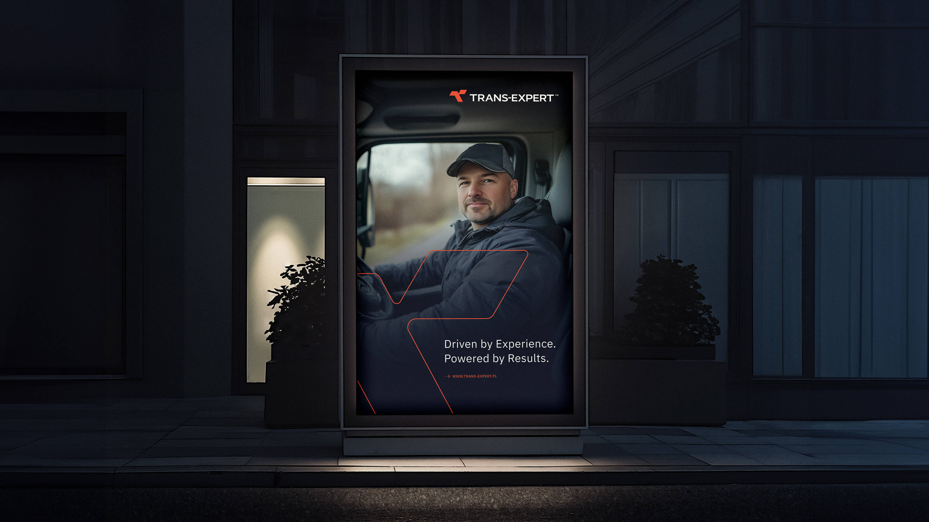 Illuminated outdoor advertising display showing a man in a cap sitting in a truck cab, with the Trans Expert logo and the slogan 'Driven by Experience. Powered by Results.