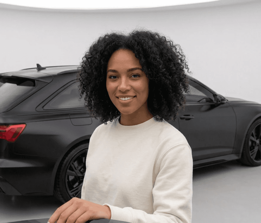 Young woman with curly hair standing beside her Audi RS6 Avant