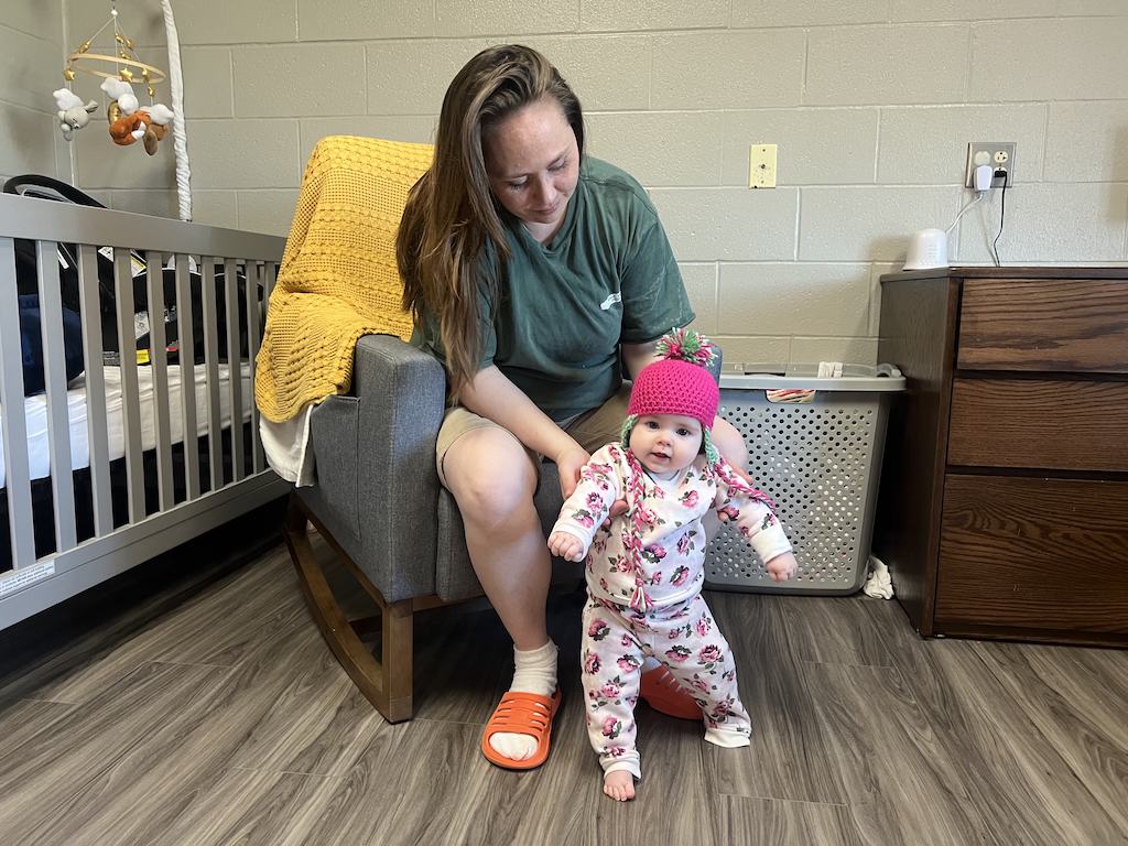 Kaley McDowell helps her daughter Kimber stand while sitting in a rocking chair in their room.