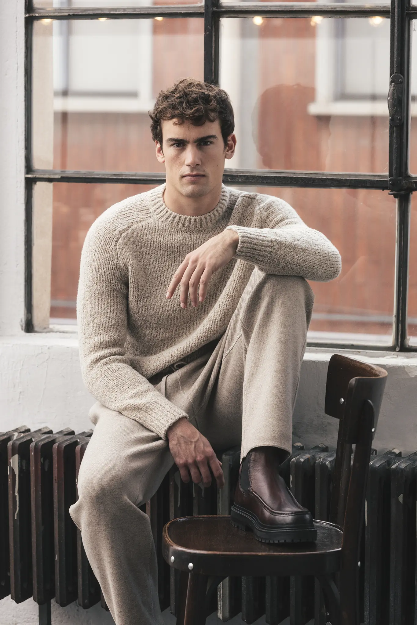 Man wearing beige cashmere crewneck sweater and matching trousers, styled with dark brown boots – Aida Barni FW25/26.