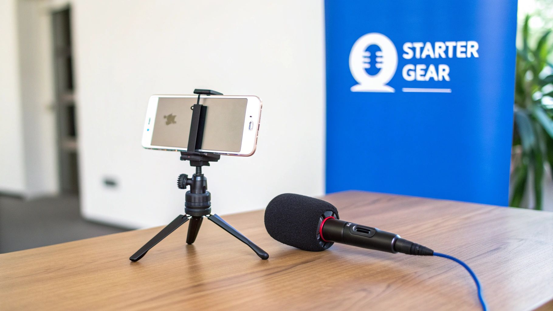 A minimalist desk setup showing a smartphone on a tripod, a small ring light, and a lavalier microphone.