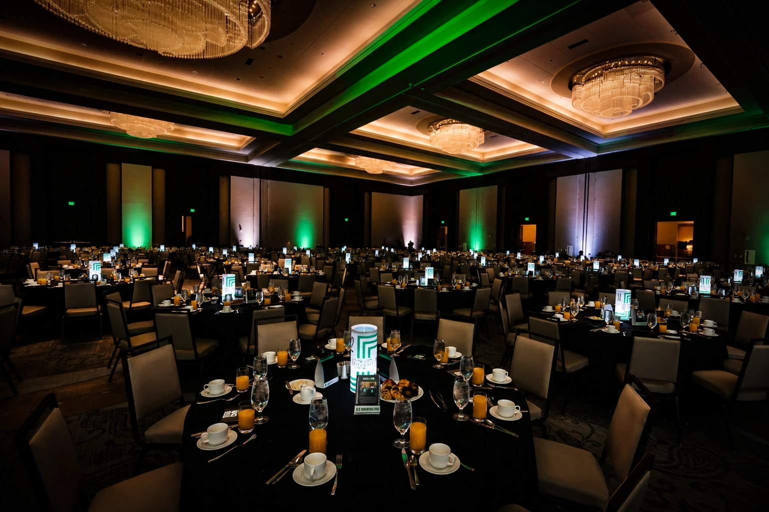 Dinner tables with place settings under green and purple uplighting at the Big Breakfast, Nashville — event lighting by UpLight Technologies