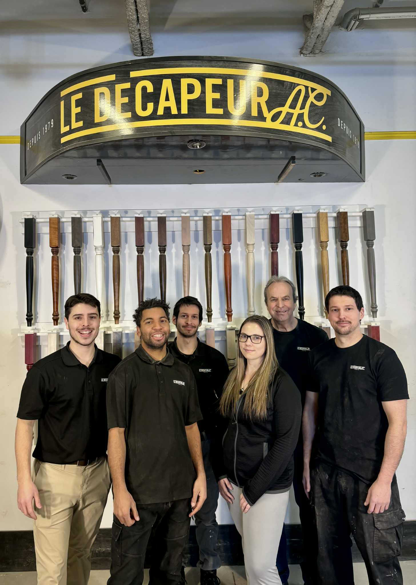 Un employé décape un meuble en bois à l'aide d'une ponceuse