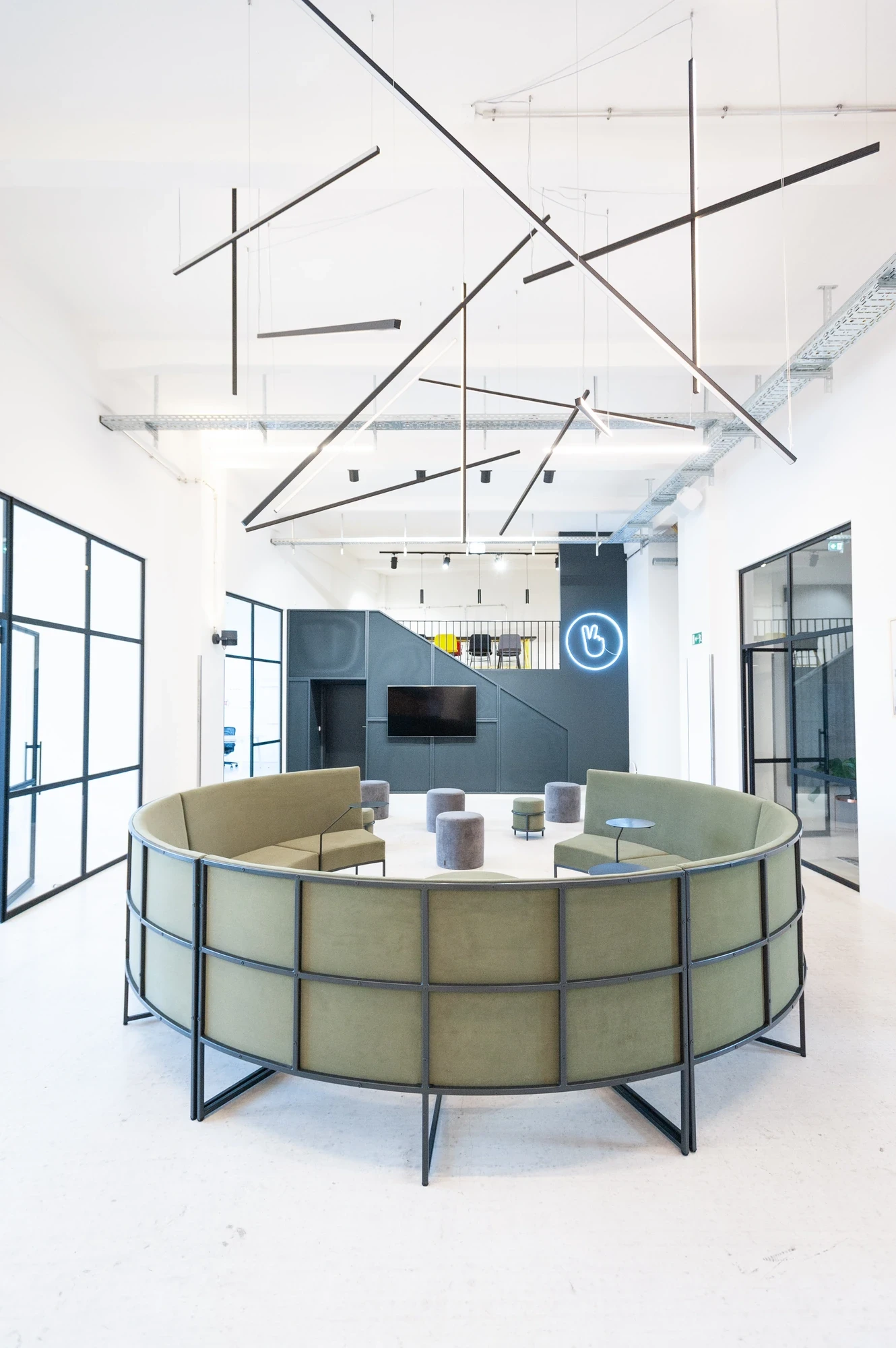 Bright minimal office with a white mesh grid divider, blue accent light strip on the ceiling and a meeting room visible through the partition.