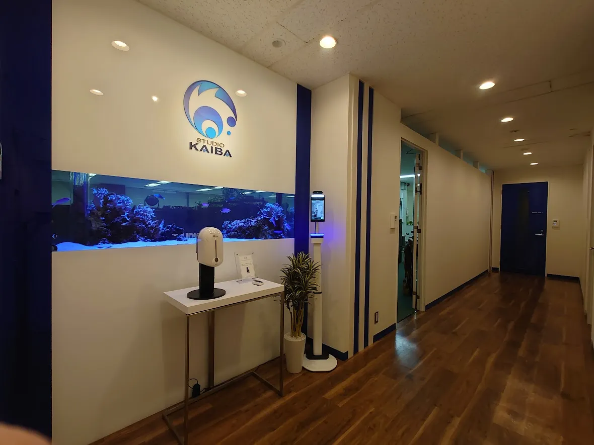 オフィスエントランスに設置された壁埋め込み型の海水水槽と、ロゴサインが一体化した空間デザイン