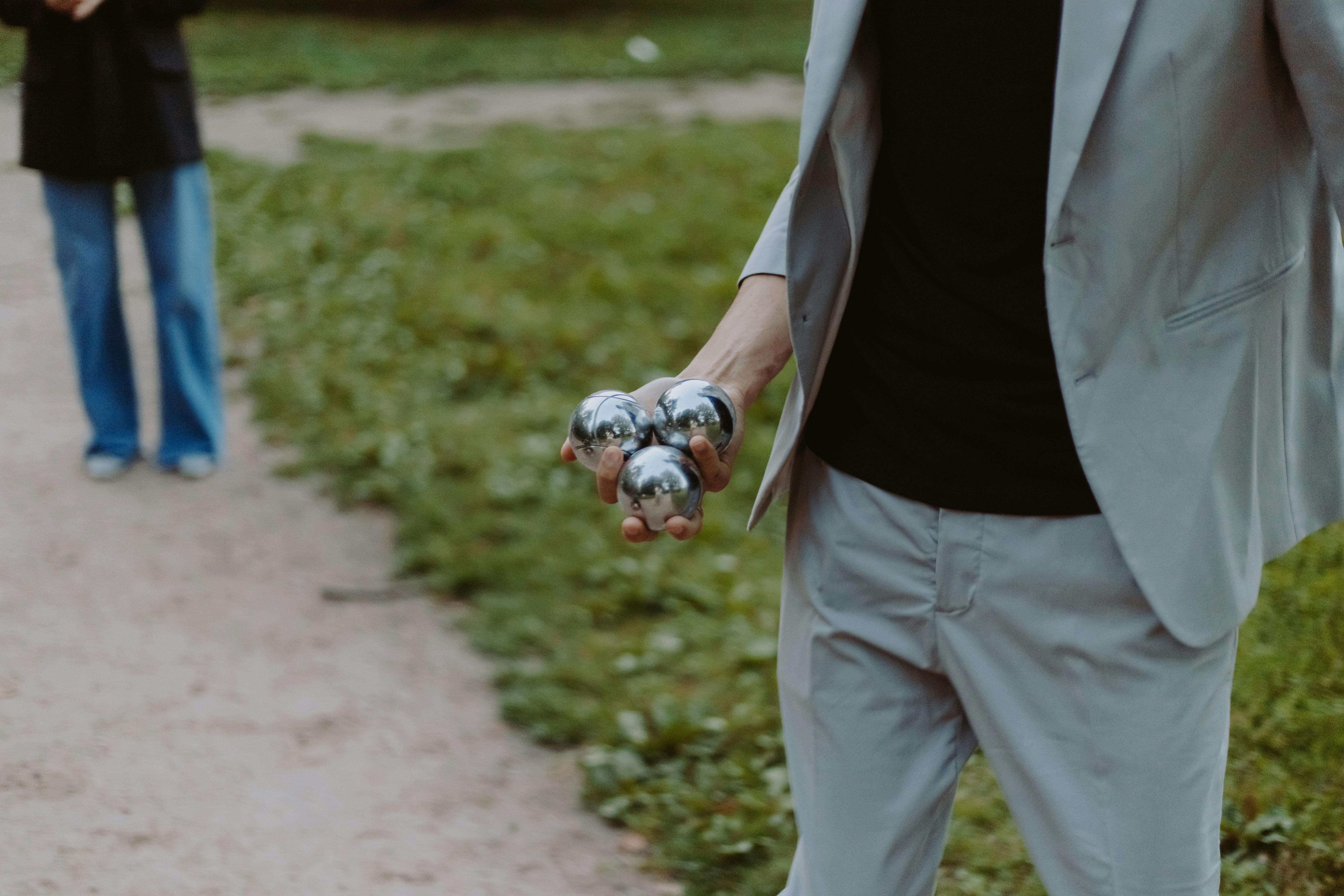 A young person with curly hair smiles at the camera while sitting in front of a laptop against a dark background.