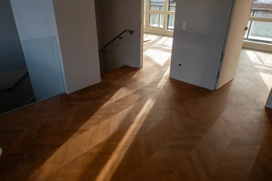Licht fällt durch offene Türen auf frisch verlegten Parkettboden in warmem Holzton.