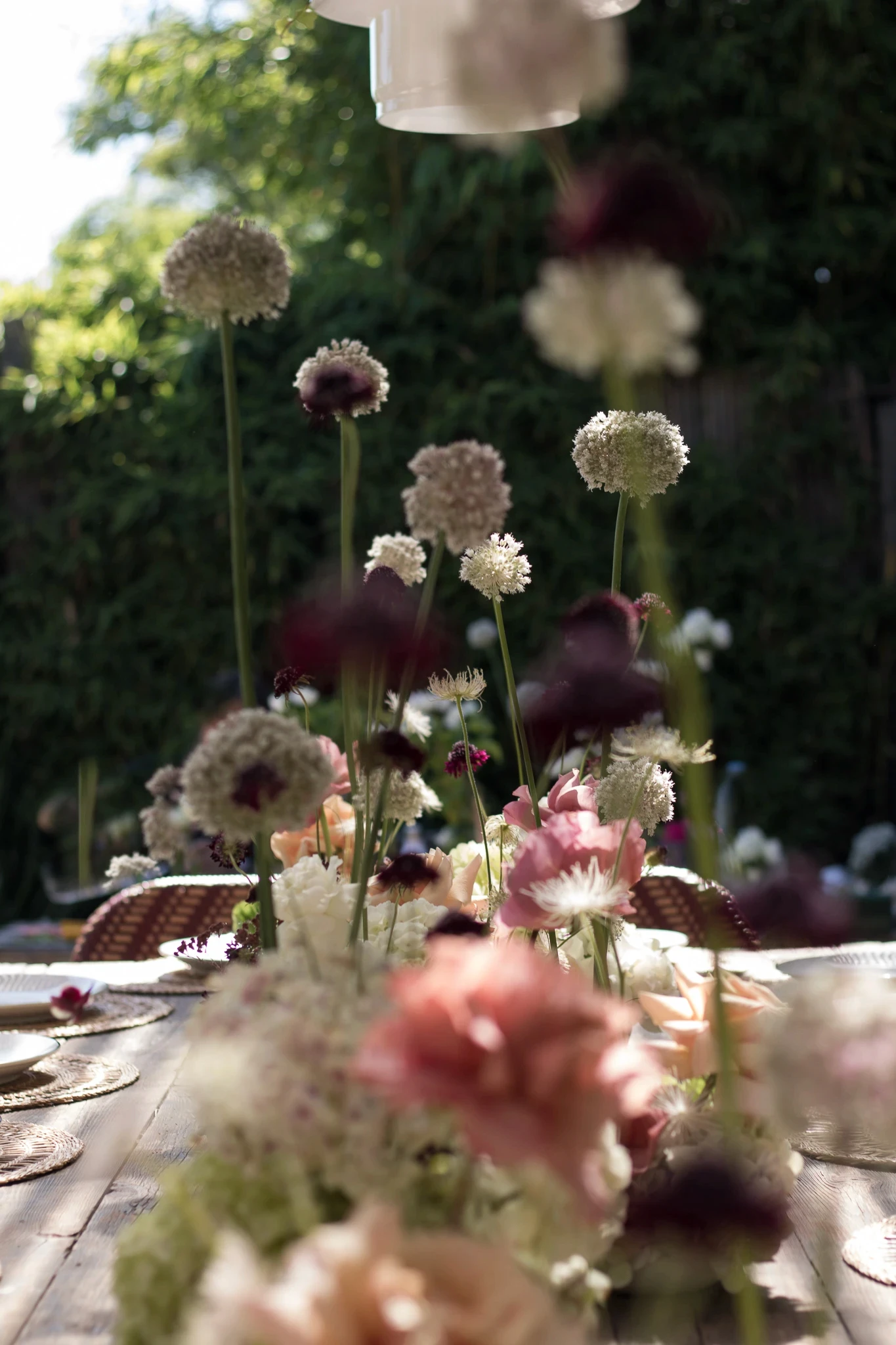 Primer plano de flores silvestres blancas y rosas sobre mesa de madera con fondo de jardín desenfocado.
