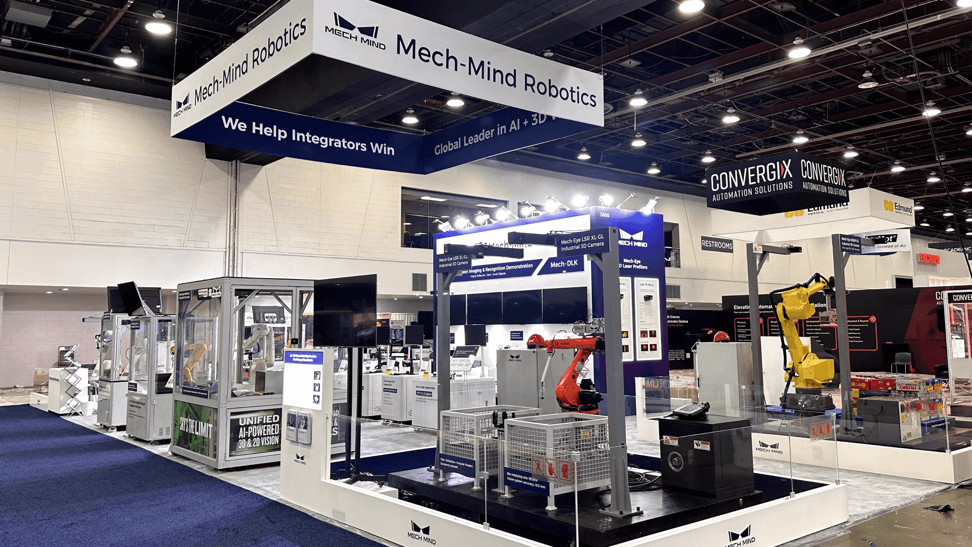 Mech-Mind Automate 2025 robotics product demo booth with robot arm displays, demo stations, overhead signage, and industrial technology presentation