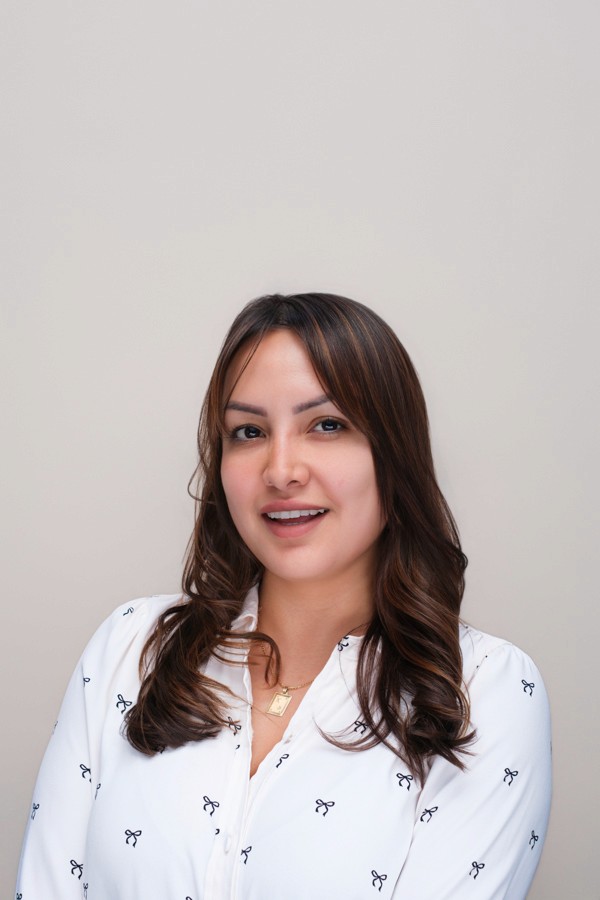 Professional headshot of a woman in a white patterned blouse
