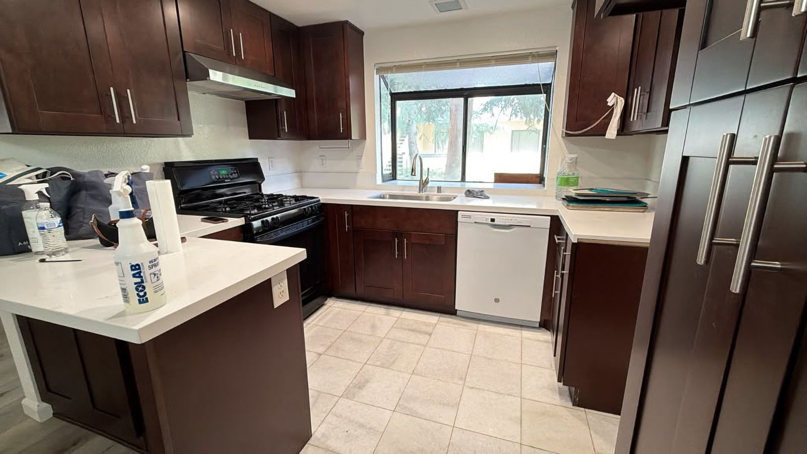 Empty kitchen with dark cabinets and white counters after a move-out cleaning
