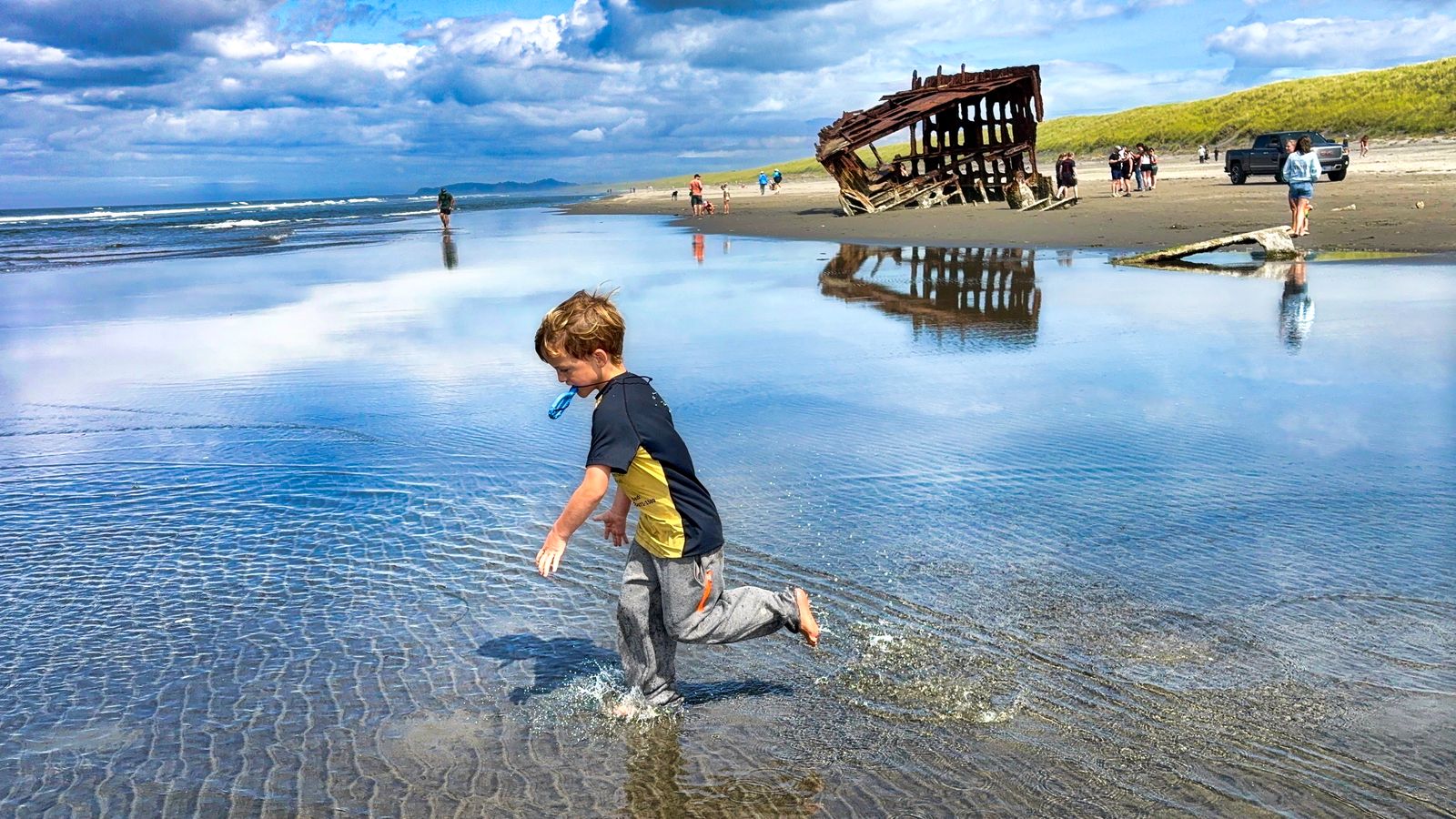 Hyrum splashing through the shallow water beside the Peter Iredale shipwreck