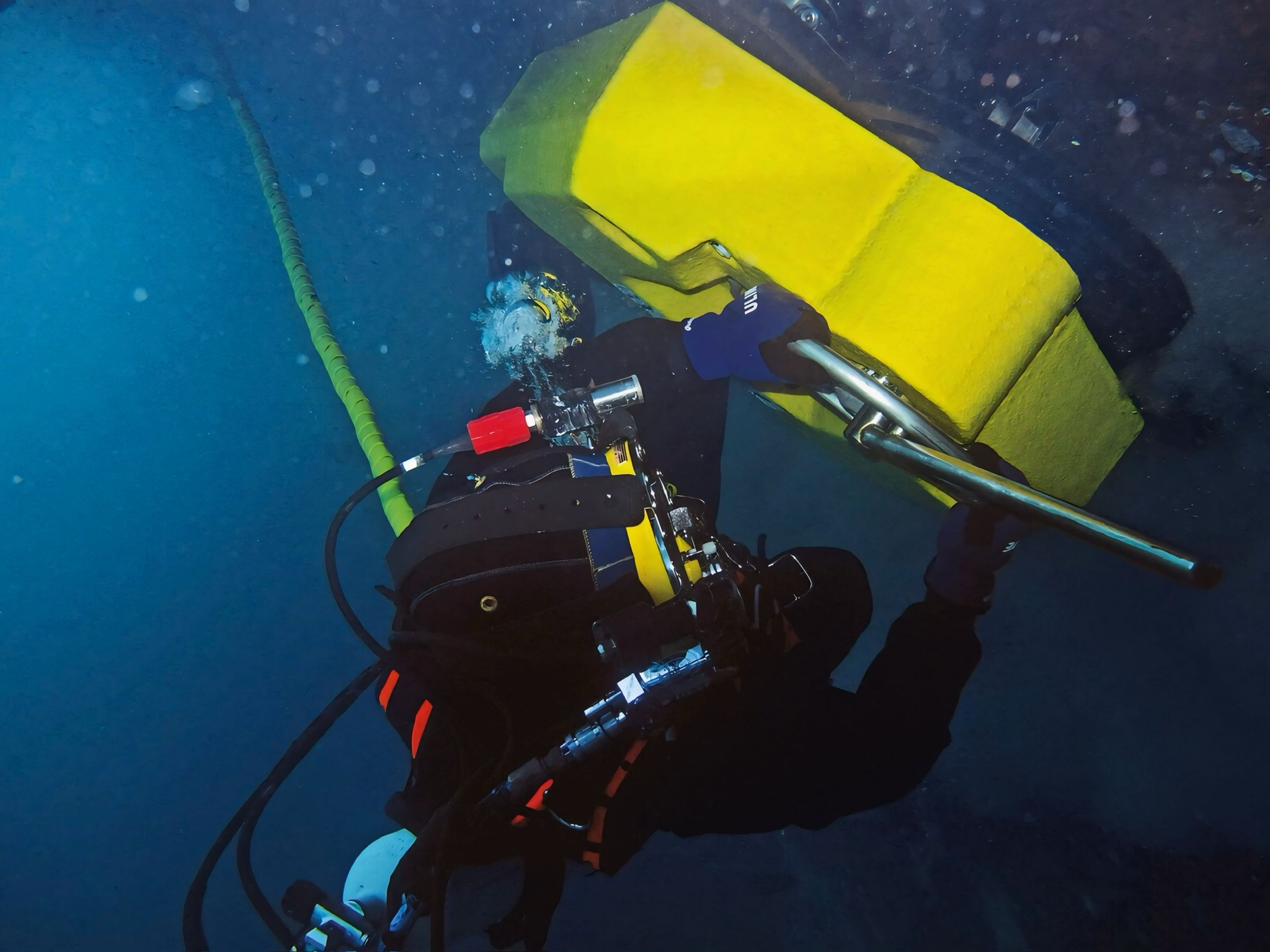 Commercial diver performing in-water hull cleaning work near a ship’s thruster/appendage area using controlled tooling—targeted underwater cleaning and inspection-ready documentation.