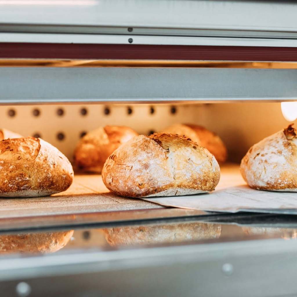 Freshly baked sourdough loaves cooling in an oven, showcasing their golden crusts and soft interiors.