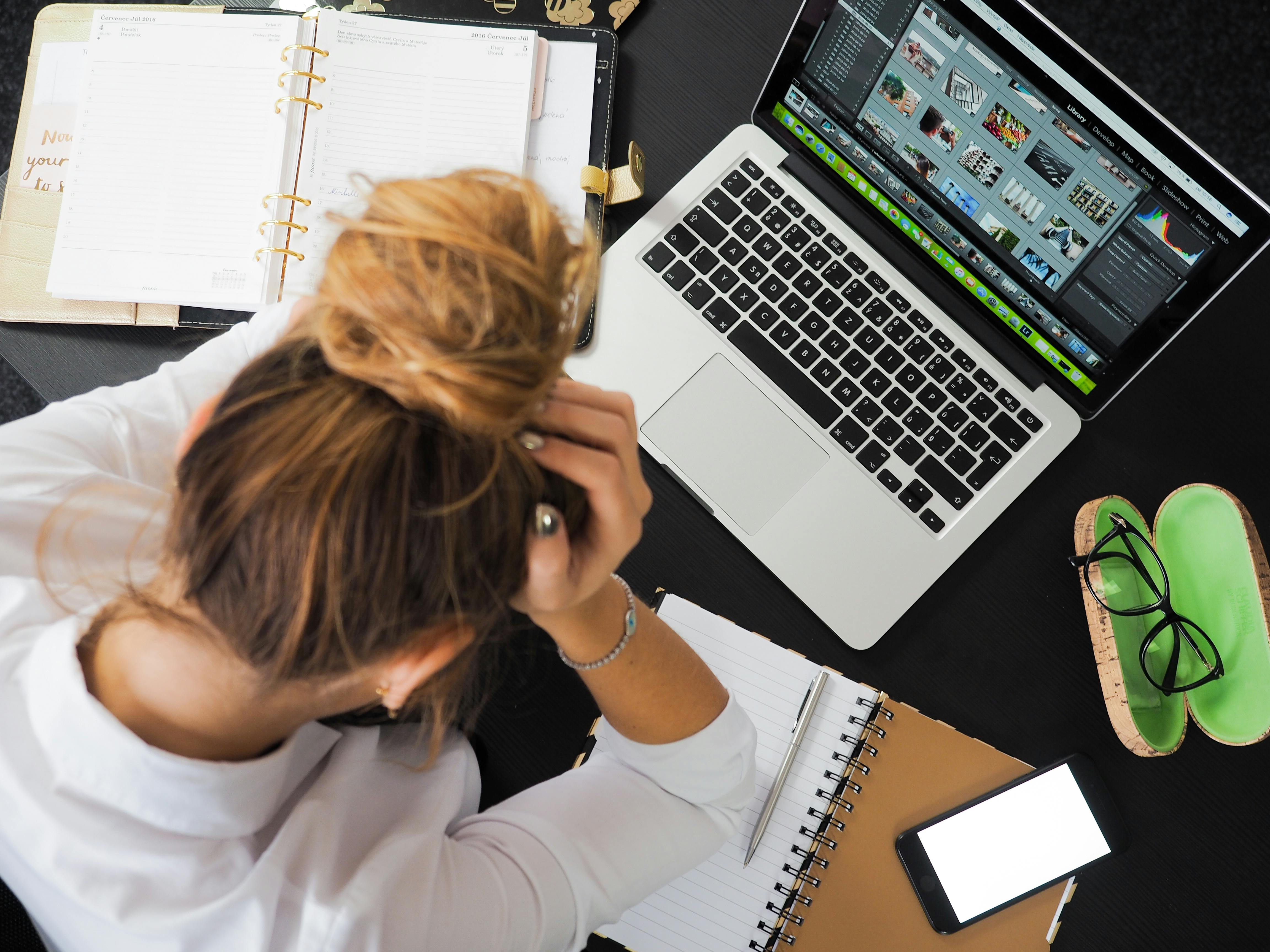 Woman sitting in front of a laptop, scratching her head, symbolizing brainstorming or problem-solving during work or interview preparation.