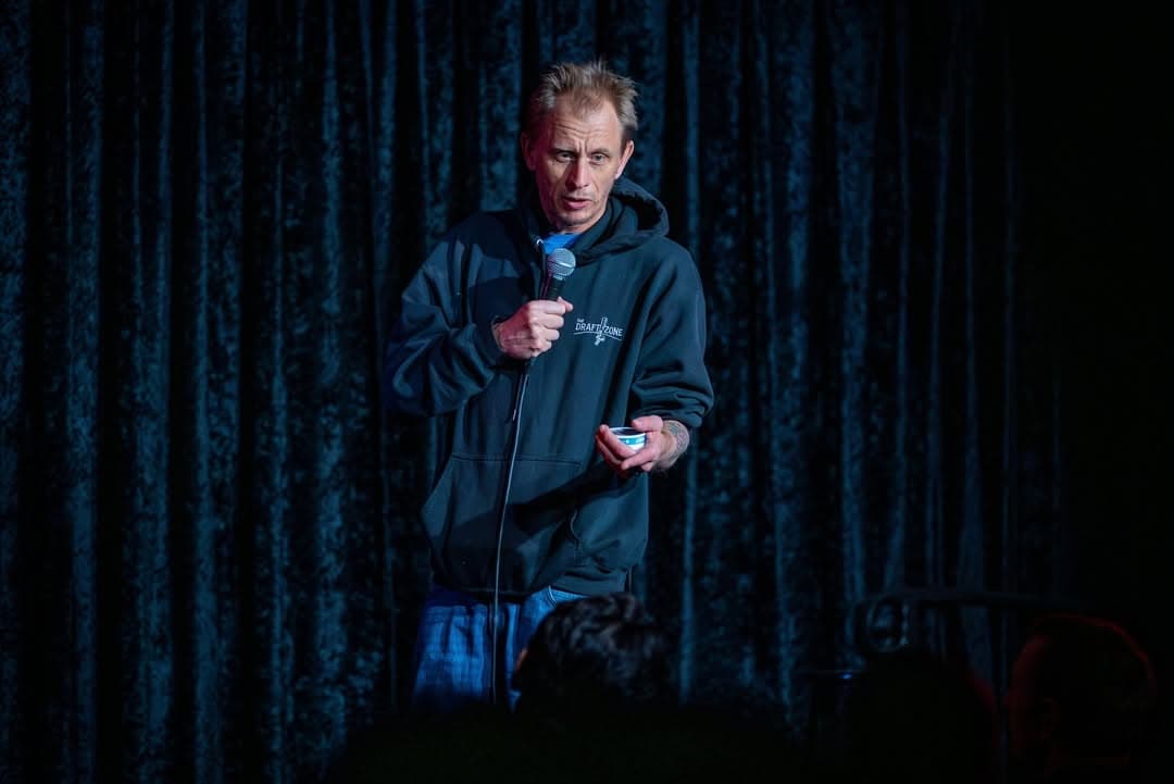 Davey Wester performing Stand Up Comedy and holding dip