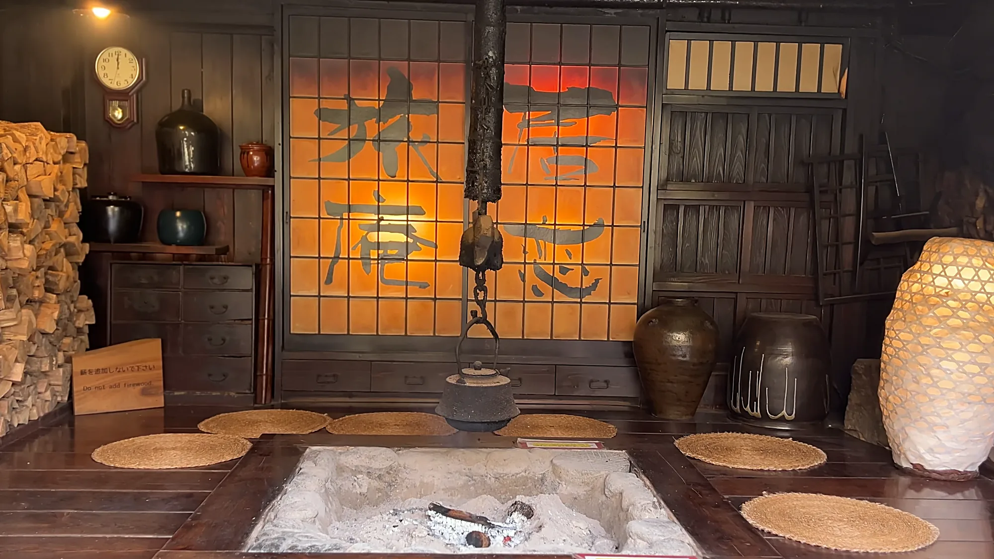 An irori hearth room at Kurokawa Onsen, a kettle on a chain above straw mats
