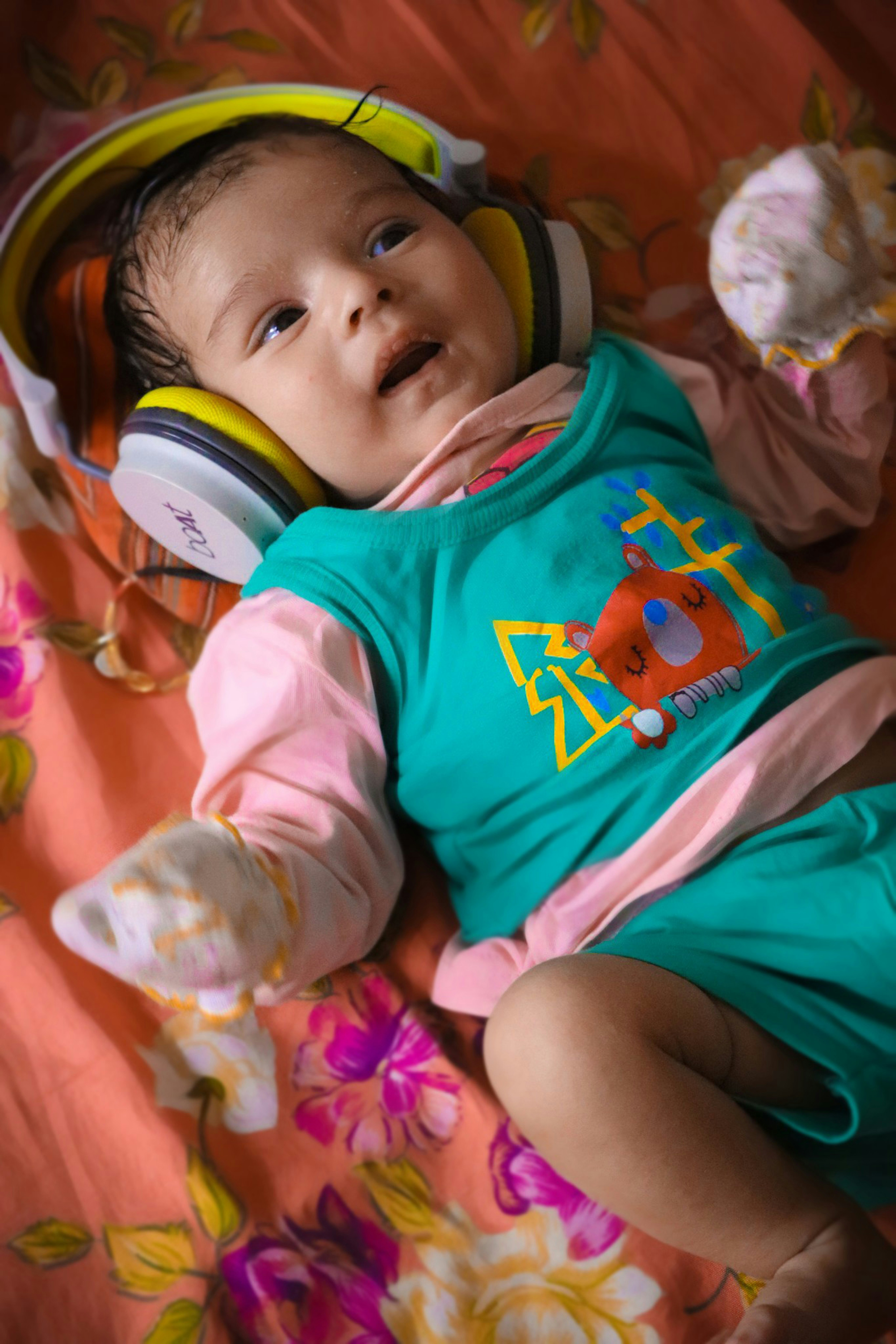baby in green and white long sleeve shirt lying on pink textile