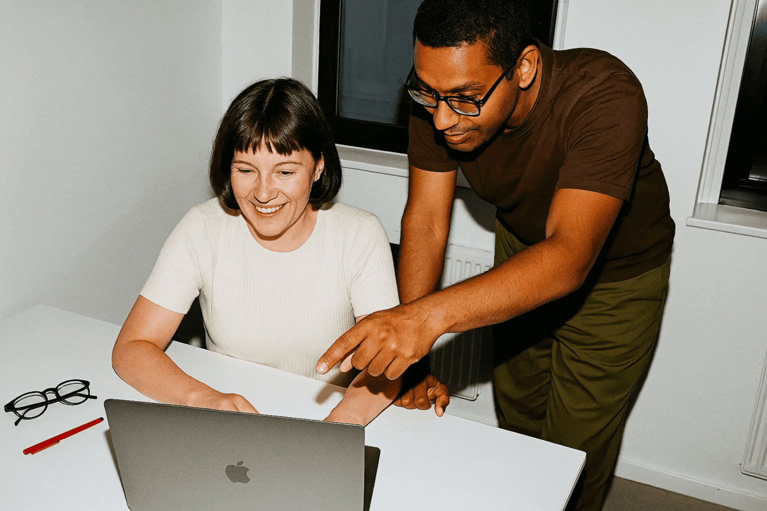 Two colleagues smiling while working together on a laptop.