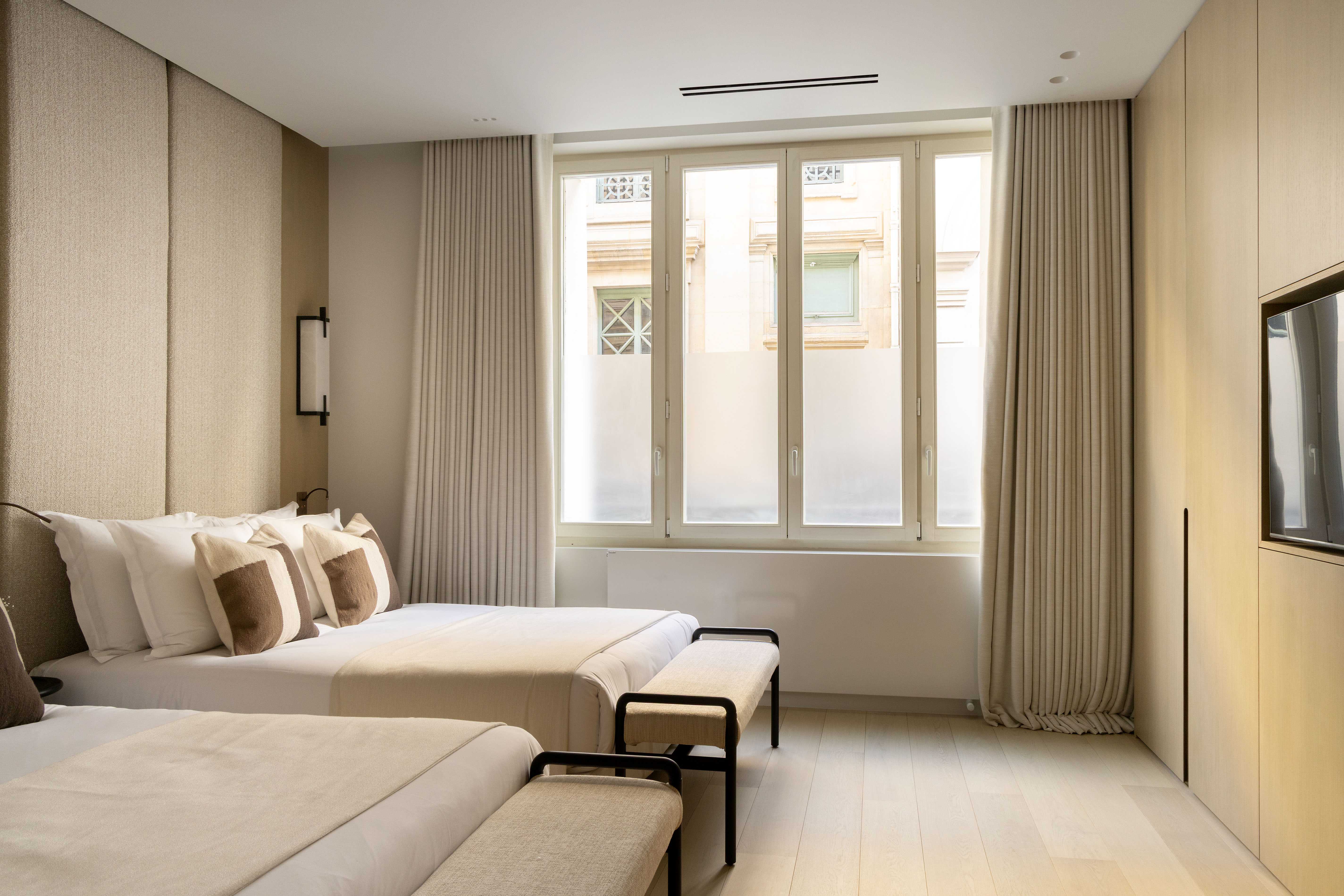 Seconde chambre avec deux lits jumeaux, fenêtres donnant sur la cour, banquettes et télévision