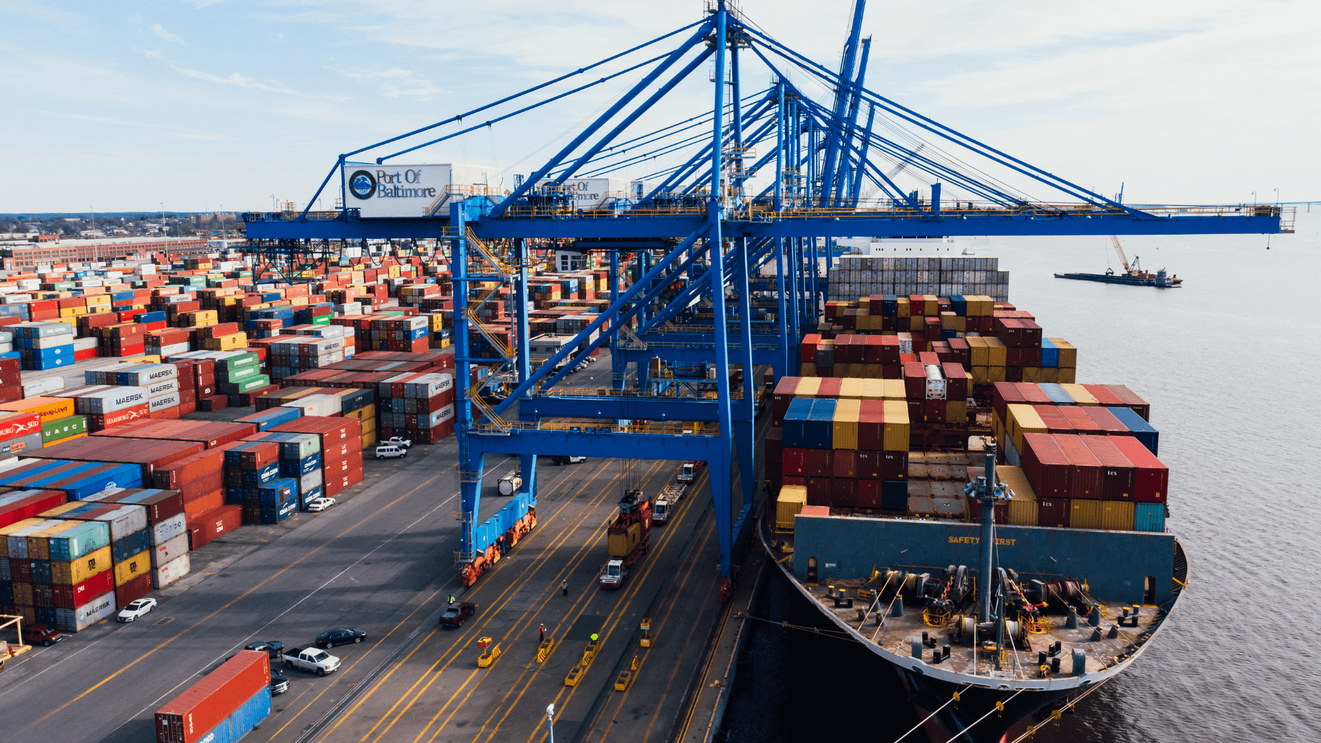 Aerial view of a busy container terminal with ship-to-shore cranes loading a cargo vessel.