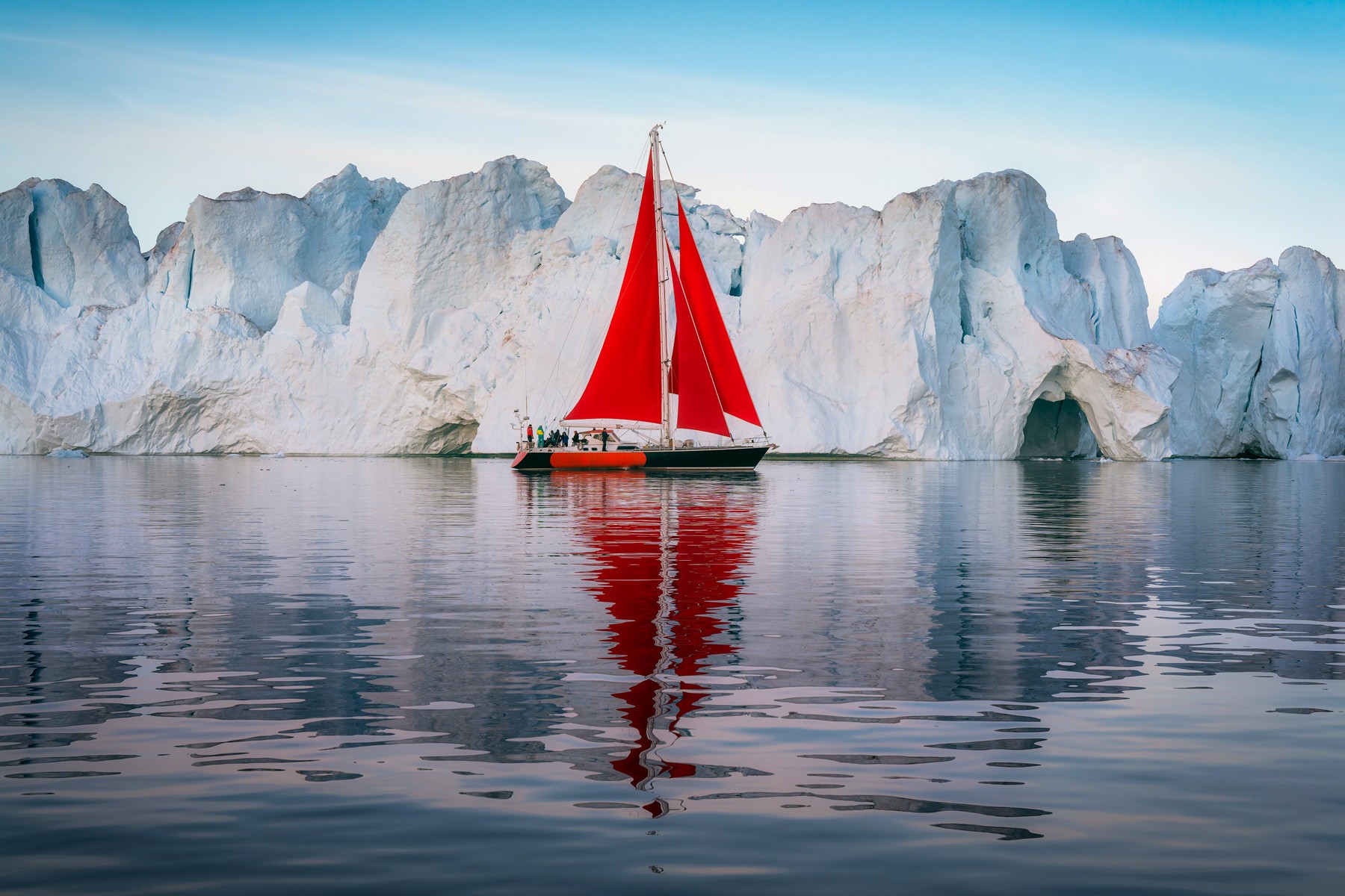 Velero rojo navegando en la bahía de Disco en Groenlandia