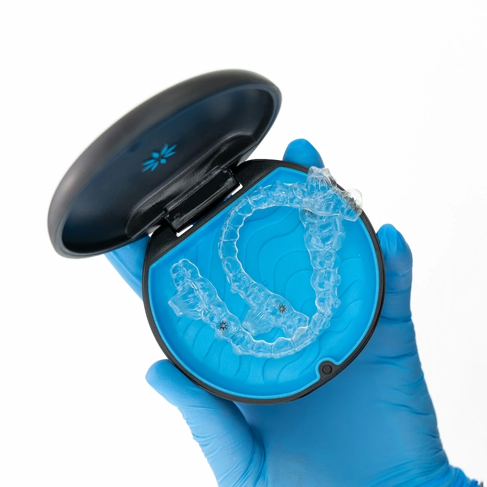 a box with clear aligners inside held in a gloved hand