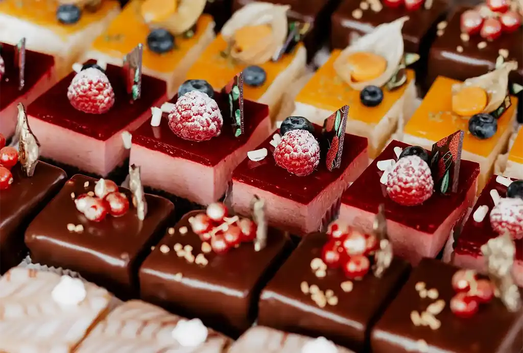 A colorful bowl with avocado, mixed vegetables, and chicken, accompanied by a side of greens and an orange.