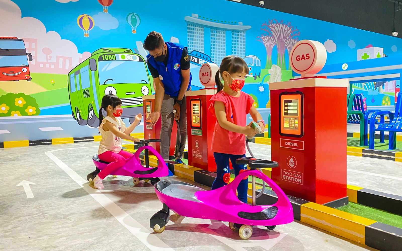 Children playing at Tayo Station gas pump area with colorful cartoon backdrop.