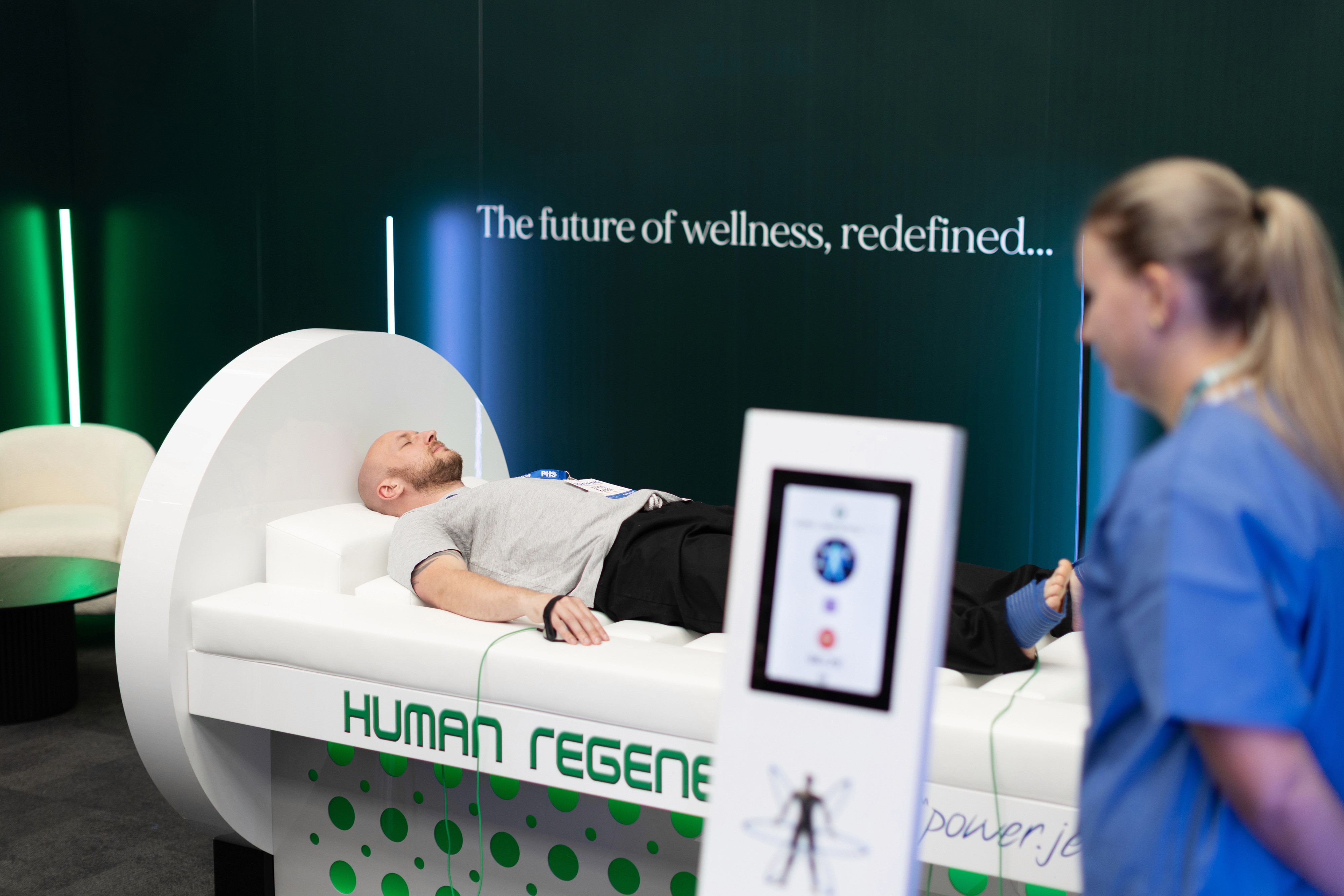 Cozy reading nook with sofa, chair, and plants inside a glass cabin with mountain forest views.