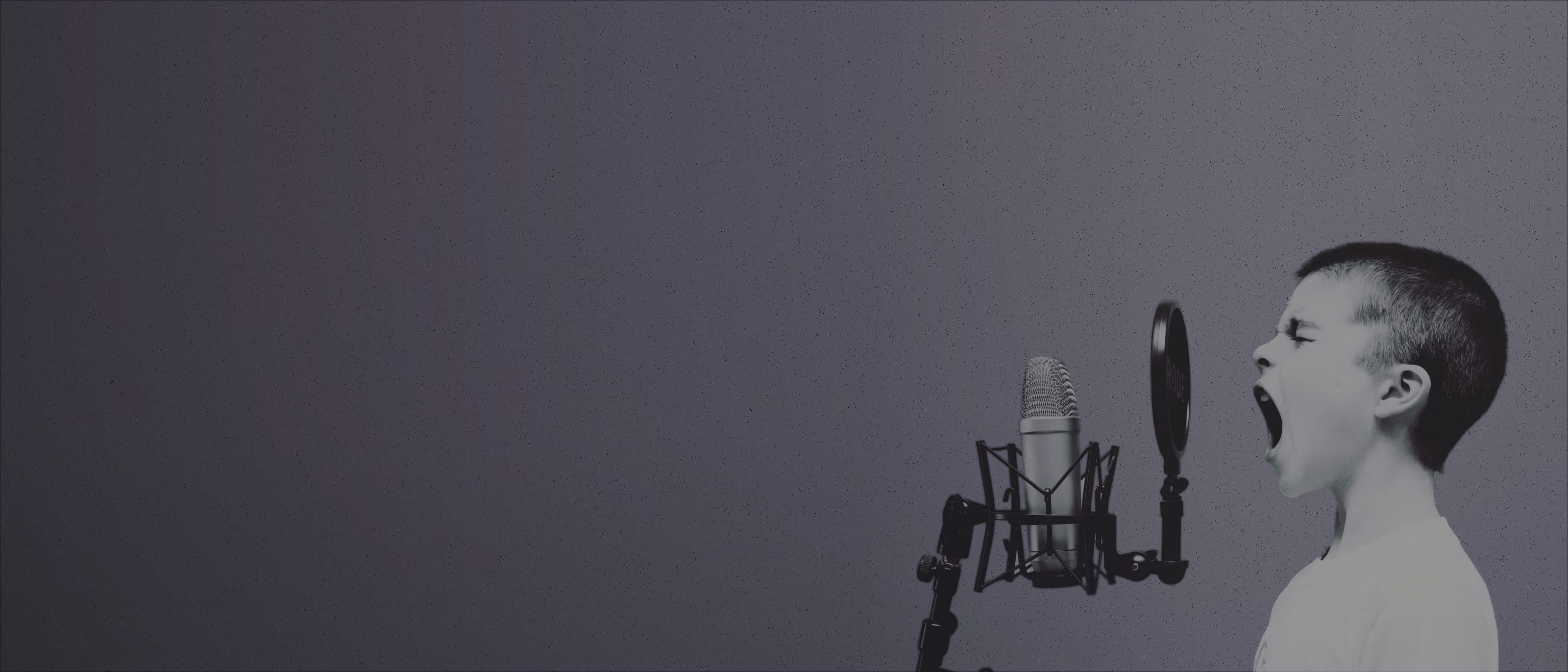 A photo of a young boy shouting into a microphone