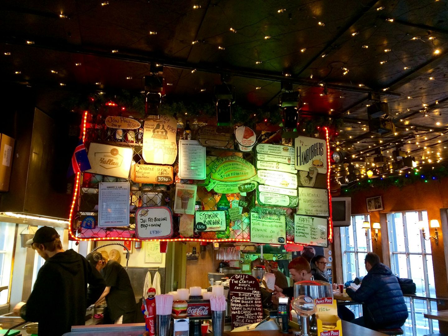 Interior of Hamborgarabúlla Tómasar (Tommi's Burger Joint) in Reykjavík with its colorful menu boards and open kitchen.
