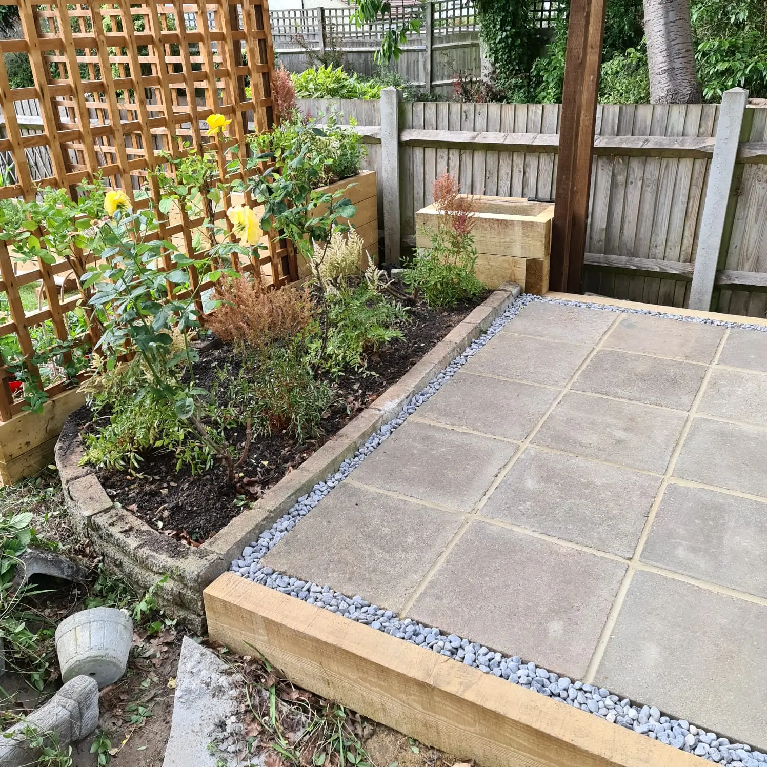 A stone patio area surrounded by plants and wooden fencing, creating a cozy outdoor space.