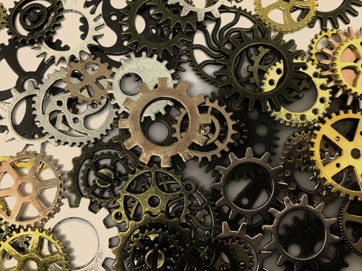 A collection of metallic clock gears in various shapes and sizes, featuring black and gold colors.