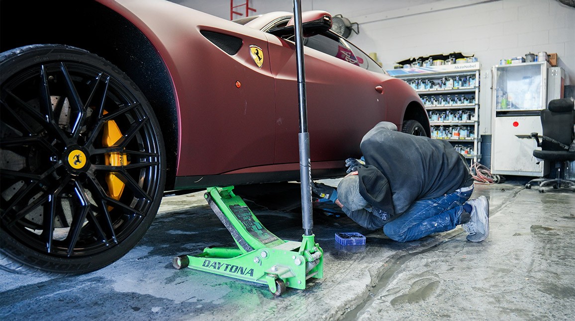 Auto Body Unlimited technician securing a Ferrari during vehicle intake after towing.