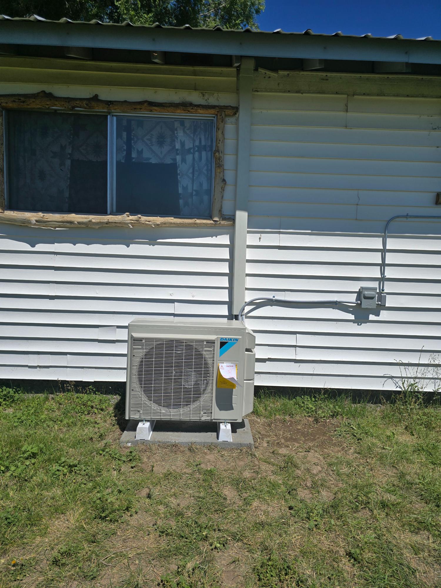 Daikin outdoor heat pump unit installed against a home’s siding.