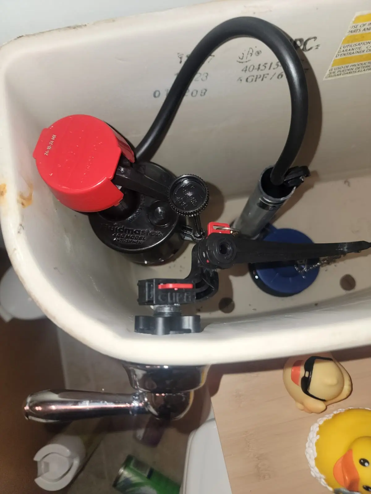 An inside view of a toilet tank showing a new fill valve and flapper replaced during a professional toilet repair.