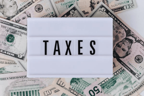 Taxes sign on a background of US dollar bills, related to filing taxes for a divorce law firm in the USA